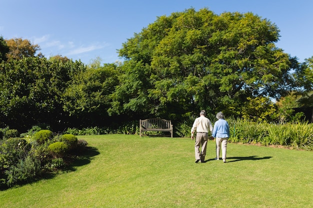 Starsza kaukaska para spacerująca razem w słonecznym ogrodzie. koncepcja rekolekcji, emerytury i szczęśliwego seniora.