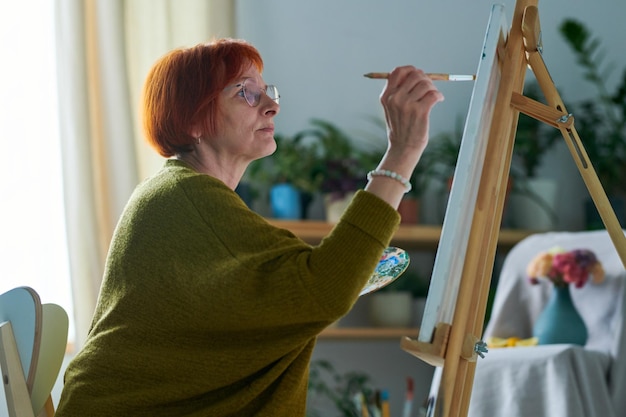 Starsza kobieta aktywna w czasie wolnym, malująca obraz
