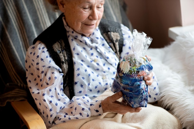 Starsza kobieta cieszy się paczką słodyczy prezentem gwiazdkowym dla seniora domu opieki