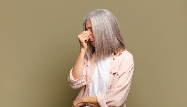Starsza Kobieta Czuje Się Zestresowana, Nieszczęśliwa I Sfrustrowana, Dotyka Czoła I Cierpi Na Migrenę Lub Silny Ból Głowy