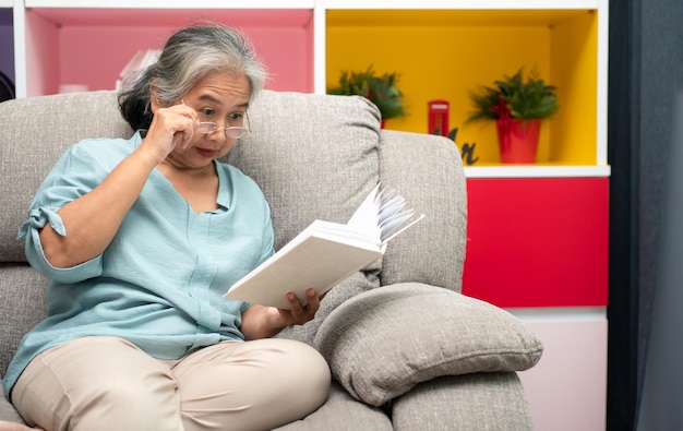 Starsza kobieta czytająca książkę ciesz się i zrelaksuj zostań sama w domu Ciesząc się emeryturą