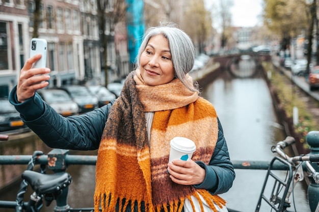 Starsza kobieta je śniadanie w Amsterdamie i robi sobie selfie