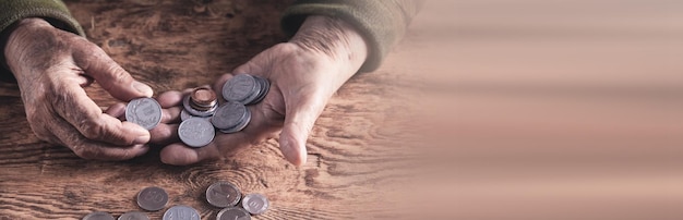 Starsza kobieta liczy pieniądze na drewnianym stole