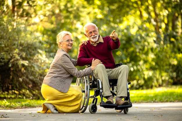 Zdjęcie starsza kobieta opiekuje się starszym mężczyzną na wózku inwalidzkim i okazuje miłość i szacunek