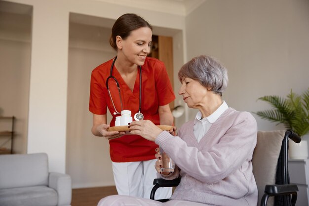 Zdjęcie starsza kobieta otrzymująca pigułki od pracownika opieki zdrowotnej w domu opieki