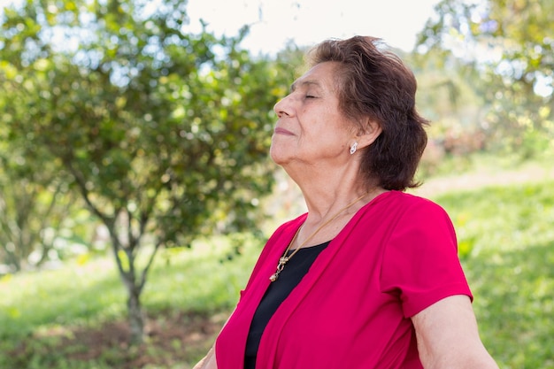 Starsza kobieta po osiemdziesiątce ciesząca się świeżym i zdrowym porankiem w lesie otoczonym zielenią