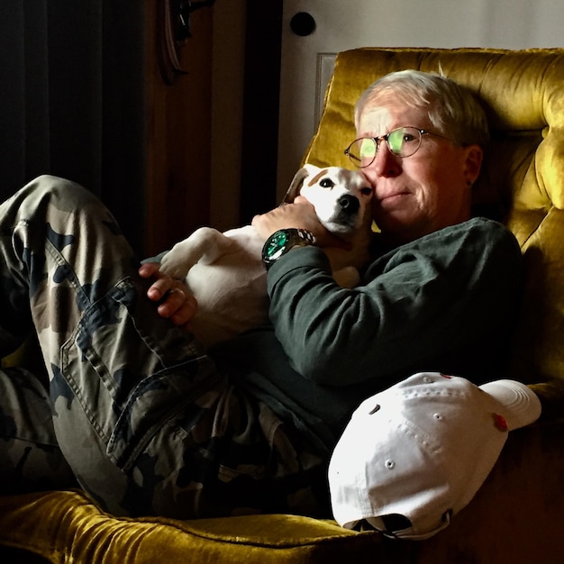 Zdjęcie starsza kobieta relaksująca się z psem na kanapie w domu