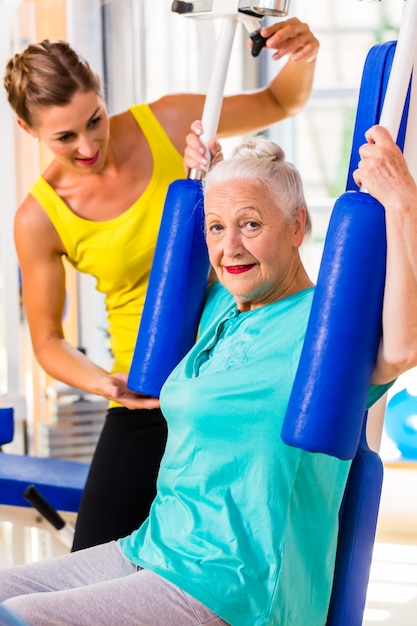 Starsza kobieta robi sprawność fizyczna sportowi w gym lub zdrowie klubie