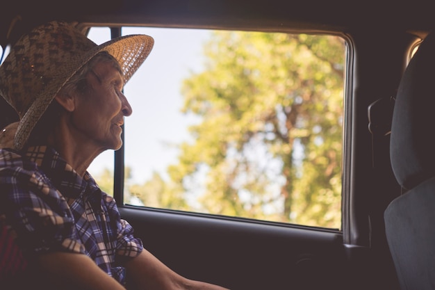 Starsza kobieta siedzi na tylnym siedzeniu w samochodzie i zagląda w okna into