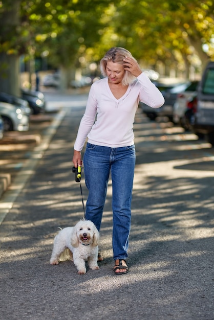 Starsza kobieta spaceru z psem na zewnątrz.