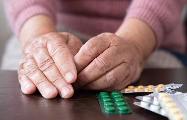 Starsza kobieta, starsza pani przyjmuje leki Starsza pani, w dłoniach trzyma tabletkę i szklankę wody