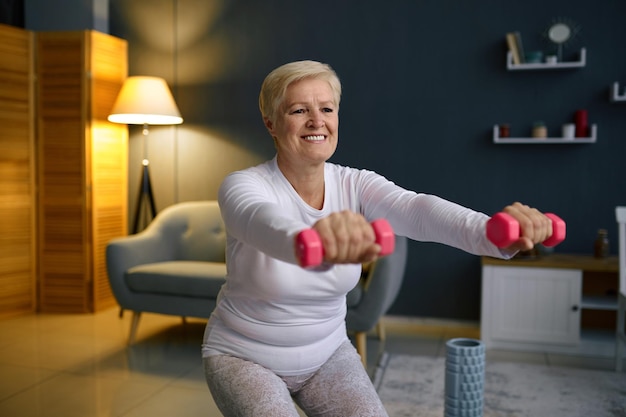 Starsza kobieta trening z hantlami w domu. Trening fitness na kwarantannie. Pielęgnacja ciała na emeryturze
