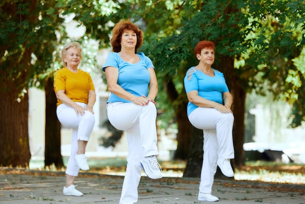 Starsza kobieta trenuje razem w parku wczesnym słonecznym rankiem, wykonując ćwiczenia cardio Koncepcja sportu i zdrowia, aktywny tryb życia, wiek, wellness pielęgnacja ciała