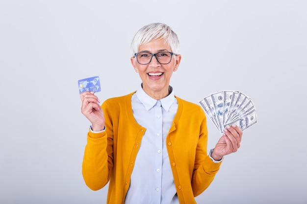 Starsza kobieta trzyma pieniądze dolarowych rachunki i kartę kredytową w ręce.