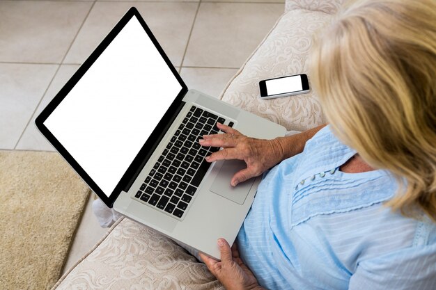 Starsza kobieta używa laptop w domu