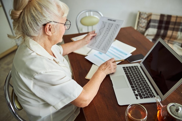 Starsza kobieta używa notatnika i robi test w domu