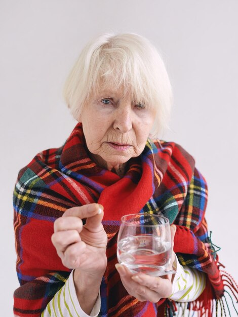 starsza kobieta w kratę w kratę z pigułką i szklanką wody Opieka zdrowotna koncepcja choroby w wieku dojrzałym