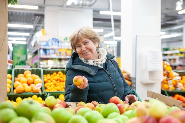Starsza kobieta zbierająca jabłko w sklepie spożywczymxDxAxDxA