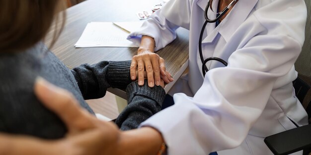 Starsza lekarzka w białym mundurze medycznym trzyma rękę pacjentki z chorobą problem zdrowotny daje wsparcie pomaga empatię i koncepcję opieki zdrowotnej ludzi