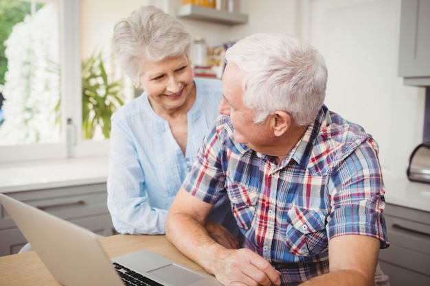 Starsza para opowiada podczas gdy używać laptop w domu
