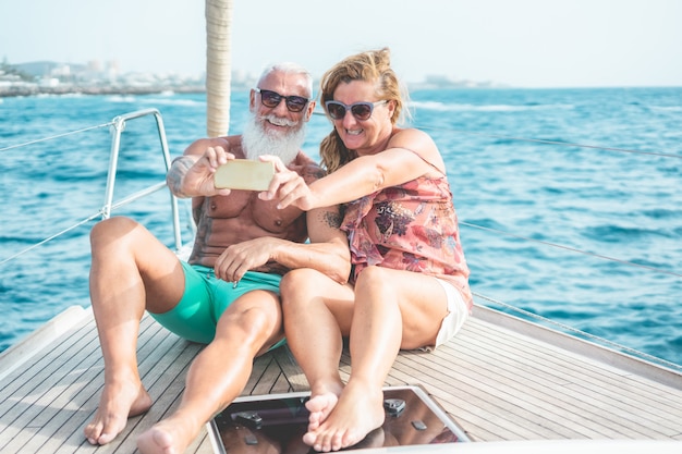 Starsza para robi selfie na żaglówce podczas luksusowego ocean wycieczki wakacje