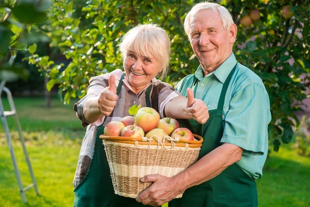 Starsza para w fartuchach kobieta na zewnątrz uśmiechnięta kciuk w górę gest zdrowie życie i sukces