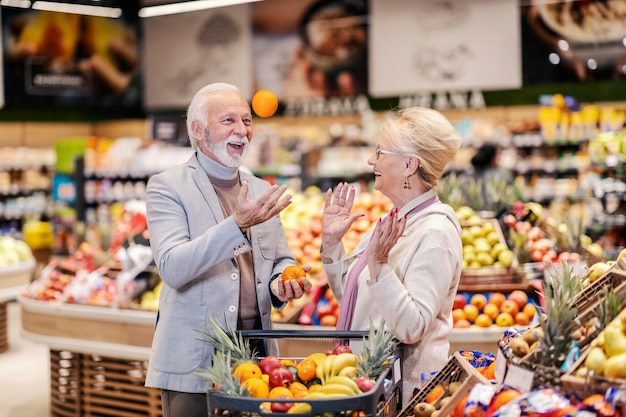 Starsza para w supermarkecie robi zakupy i śmieje się z niskich cen