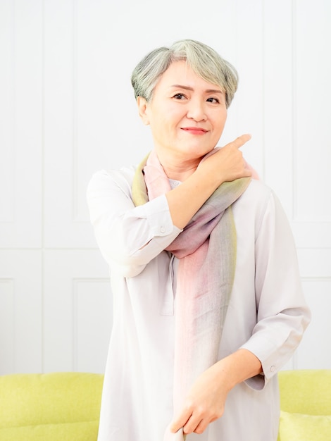 Starsza piękna siwowłosa azjatycka kobieta ubrana w casualową sukienkę i jedwabny szalik