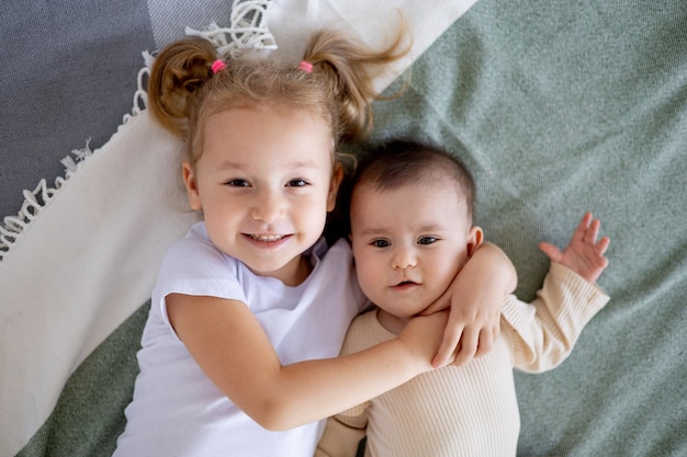 Starsza siostra trzyma i przytula dziecko w domu na łóżku miłość i przyjaźń sióstr w rodzinie