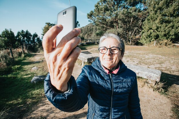 Starsza starsza kobieta robi selfie podczas ćwiczeń. Rozpoczyna nowe nawyki na nowy rok. Trekking i zdrowy styl życia. Sport kobieta emeryt. Starzenie się, ludzie, aktywny styl życia i koncepcja zdrowia