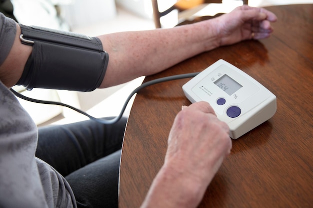 Starsza starsza kobieta sprawdza ciśnienie krwi w koncepcji domowej opieki zdrowotnej