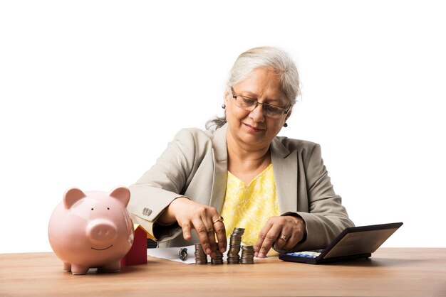 Zdjęcie starsze indyjskie lub azjatyckie kobiety biznesu oszczędzające lub trzymające lub obliczające monety walutowe. koncepcja biznesowa, finansowa i inwestycyjna