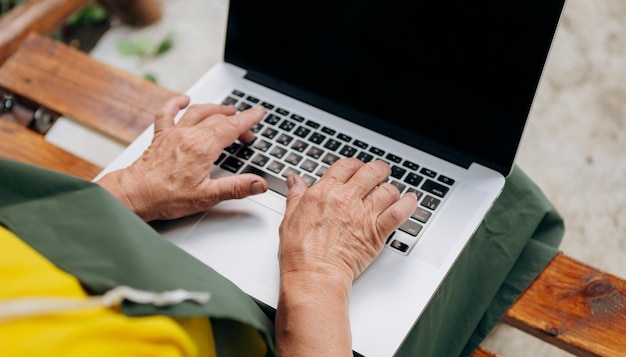 Starsze kobiece ręce wpisz tekst na klawiaturze laptopa