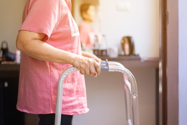 Starsze Kobiety Trzymające Się Za Ręce Chodzik Próbuje Chodzić W Domu, Koncepcja Fizjoterapii