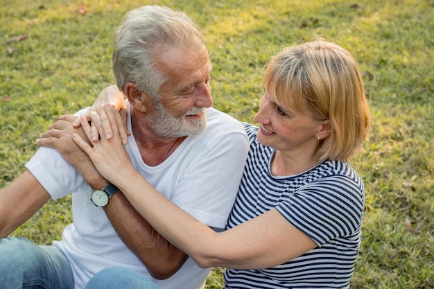 Starsze pary siedzące przytulają się i szczęśliwie uśmiechają w parku. Koncepcja starszego kochanka.
