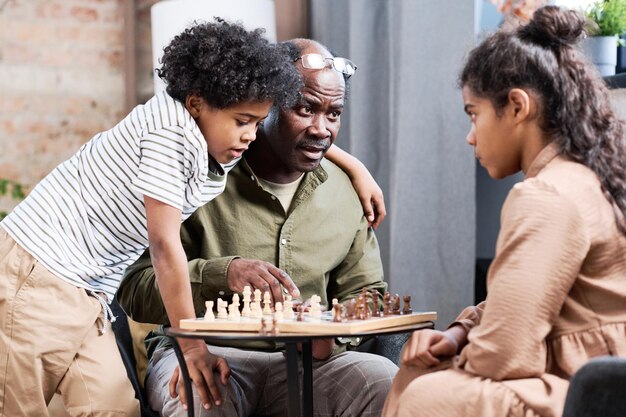 Starszy Afroamerykanin i jego dwoje wnuków grają razem w szachy