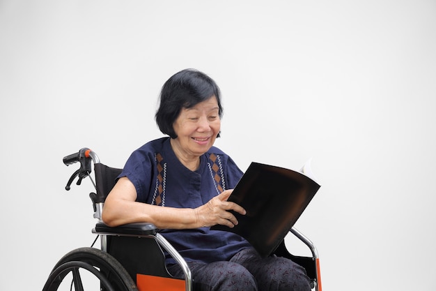 Starszy asian kobieta uśmiecha się podczas czytania magazynu na białym tle