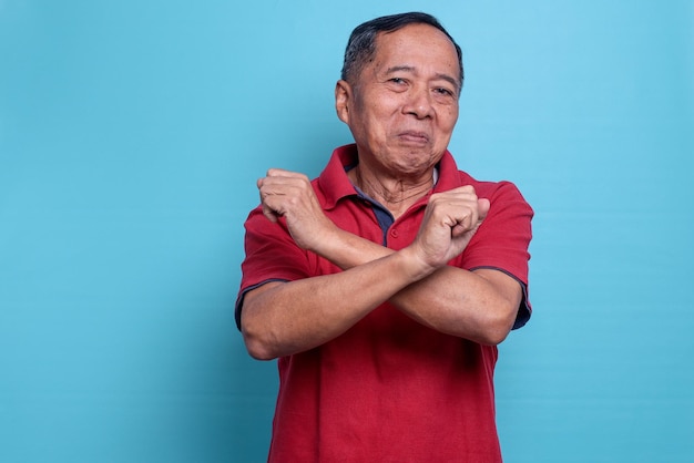 Starszy Azjat pokazujący gest odrzucenia, skrzyżując ręce i dłonie, robiąc znak negatywny