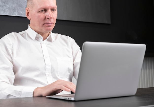 Starszy biznesmen pracuje na laptopie przy biurku wysokiej jakości zdjęcie