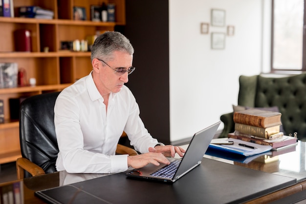 Starszy biznesmen używa jego laptop