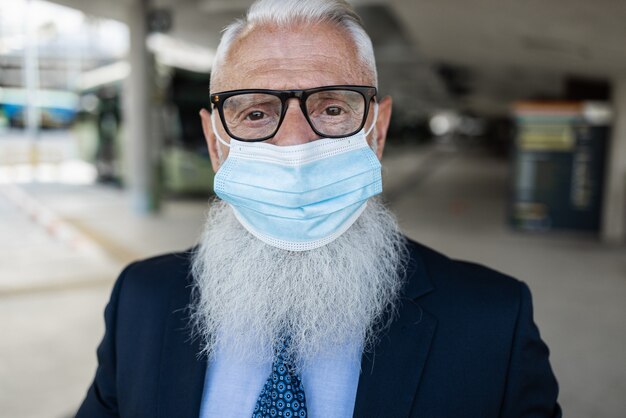 Zdjęcie starszy biznesmen w mieście w masce ochronnej na wypadek epidemii koronawirusa