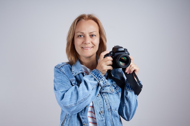 Starszy fotograf z profesjonalnym aparatem fotograficznym na szarym tle