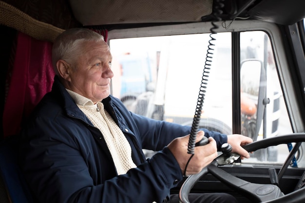 Zdjęcie starszy kierowca siedzący w kabinie dużej nowoczesnej ciężarówki