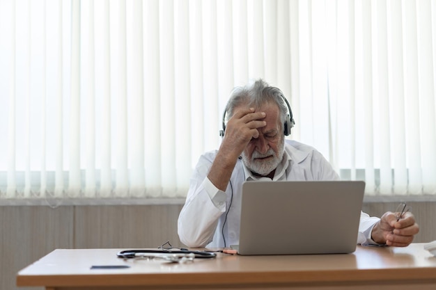 Starszy lekarz nosi zestaw słuchawkowy Zdalny czat medyczny online konsultacja telemedyczna usługi na odległość Koncepcja telezdrowia