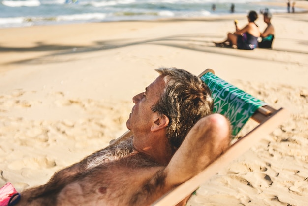 Starszy mężczyzna chłodzi na plaży