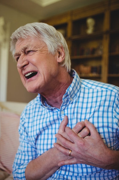 Starszy mężczyzna cierpi na ból w klatce piersiowej w salonie