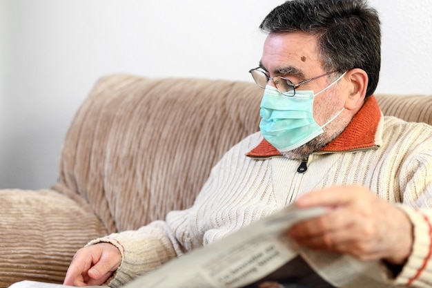 Starszy mężczyzna czyta gazetę podczas kwarantanny epidemicznej koronawirusa.