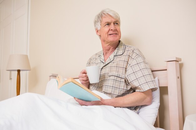 Starszy mężczyzna czyta książkę w łóżku