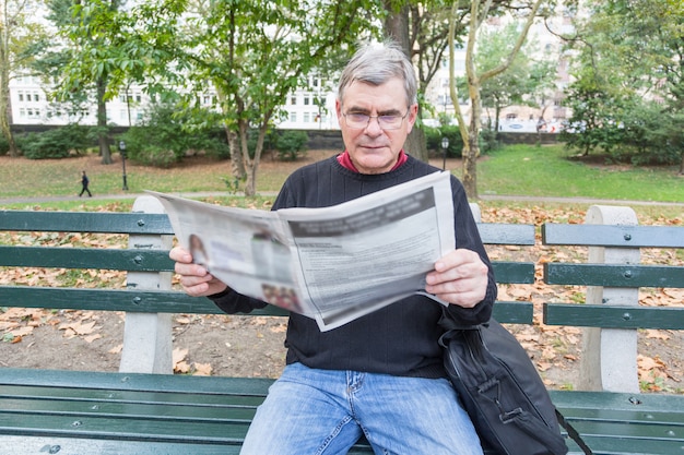 Zdjęcie starszy mężczyzna czytanie gazety w parku