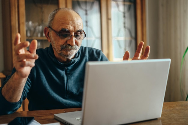 Zdjęcie starszy mężczyzna korzystający z laptopa w domu